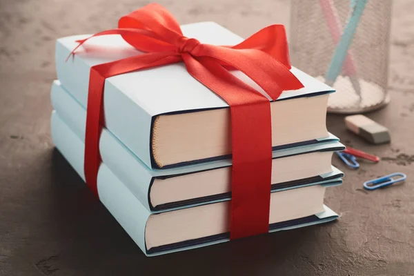 Close-up of books tied with ribbon on a dark background and a basket with pencils: concept of donating books