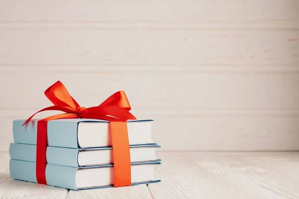 A stack of three books tied with a red ribbon with a bow and copy space: the concept of a good book - a good gift — Stok fotoğraf