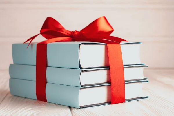 Close up of books tied with ribbon on wooden background: concept of donating books