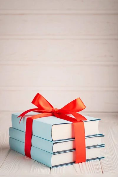 A vertical shot of a book tied with ribbon with place for text: the concept of a good book is a good gift