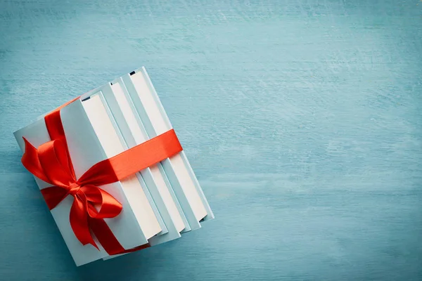 En üstteki kitap yığını mavi ahşap zemin üzerine bağlanmış bir kurdele ile fotokopi alanı ile: eğitim kavramı veya kitap hediyesi