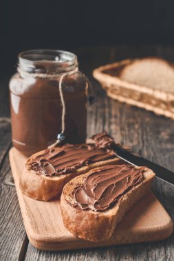 Tahta bir arka planda kesme tahtasının üzerinde çikolatalı fındık kremalı ekmek dilimleri