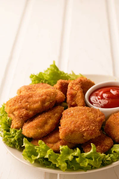 Nuggets de frango com ketchup e alface em um fundo de madeira branco com espaço de cópia — Fotografia de Stock