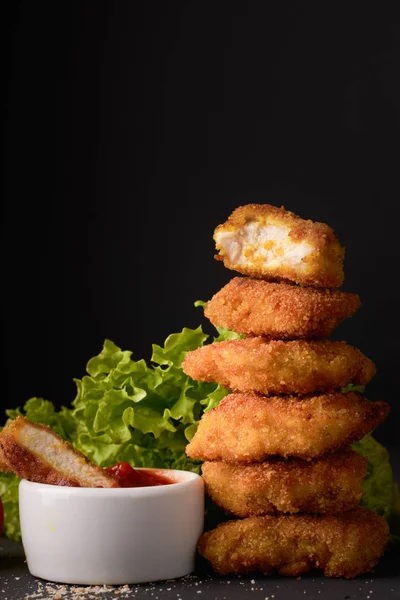 Nuggets de frango com ketchup e alface em um fundo escuro com espaço de cópia — Fotografia de Stock