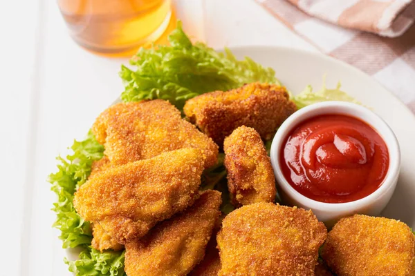 Placa llena de nuggets de pollo cocidos con lechuga y ketchup sobre la mesa — Foto de Stock