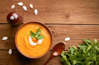 Bir kase kabak çorbasının üstünde tahta bir arka planda fotokopi alanı olan bir kaşık.