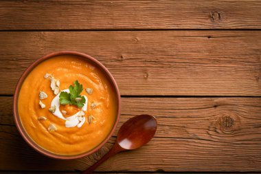 Kabak çorbası kabak tohumları serpiştirilmiş ve ahşap bir arka planda tahta kaşık ve fotokopi alanı serpiştirilmiş.