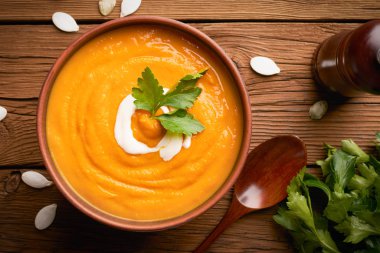 Tahta arka planda tahta kaşıkla yakın plan kahverengi balkabağı çorbası.