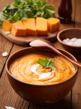 Dikey çerçeve kahverengi balkabağı çorbası ve karatahtanın üzerinde çiğ balkabağı dilimleri