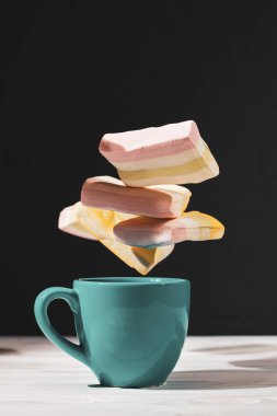 Bir fincan kakao ve siyah arka planda yükselen marşmelov.