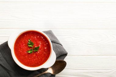 Beyaz ahşap zemin üzerinde domates çorbası kasesinin fotokopi alanı ile üst görüntüsü