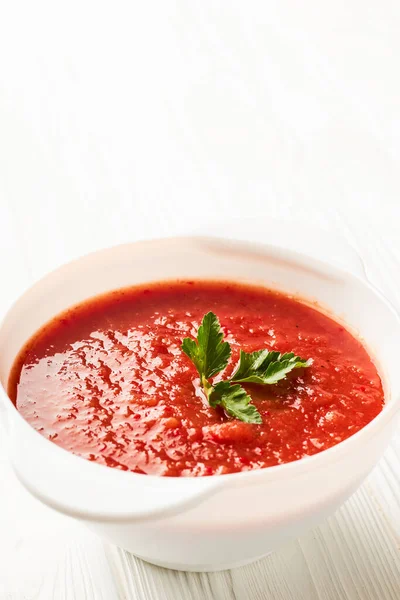 Sopa de tomate em uma tigela branca com espaço de cópia uma placa branca com um tiro vertical — Fotografia de Stock