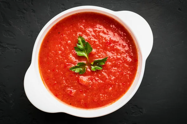 Vista dall'alto primo piano di una ciotola bianca di zuppa di pomodoro con prezzemolo su sfondo scuro — Foto Stock