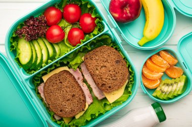Top view of school lunch boxes with sandwiches and vegetables with fruits: the concept of a healthy and balanced diet.