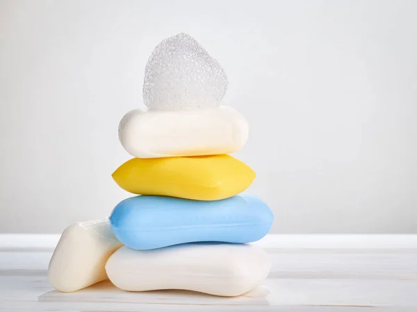 A stack of blocks of solid soap and soap foam on a light background: the concept of hygiene and cleanliness of the body.