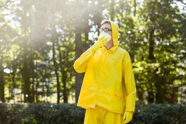 Cientista em terno protetor amarelo, óculos e respirador. Retrato do homem no fundo de árvores borradas . — Fotografia de Stock