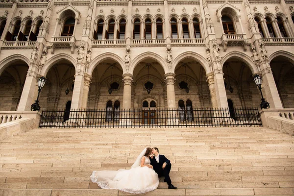 Pengantin pria dan wanita berpelukan di jalan kota tua. Pasangan pernikahan berjalan di Budapest dekat Gedung Parlemen. Pengantin pria dan wanita di tangga — Stok Foto