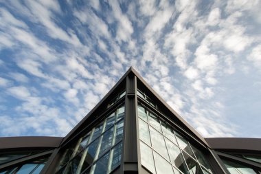 Frankfurt 'ta modern bir binanın alt manzarası. Gökyüzü arka planındaki beyaz bulutlu binanın keskin açısı. Boşluğu kopyala.