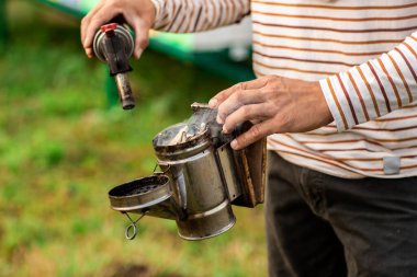 Arı yetiştiricisi arıların kovanından tüten arılar için bir araç hazırlar. Arılar için duman, arılar için ekipman. Kapat.