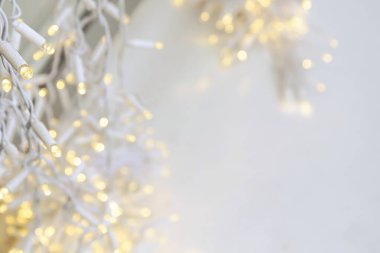 A white garland with flickering yellow lights weighs outside on a background of snow. clipart