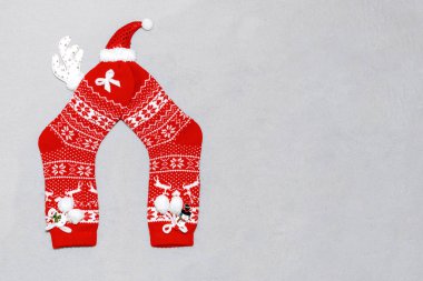 Noel kırmızı yün çorapları, geyik boynuzları, gri ekose üzerinde şapka ve kardan adam kompozisyonu. Noel konsepti, hediyeler, parti, rahat ev