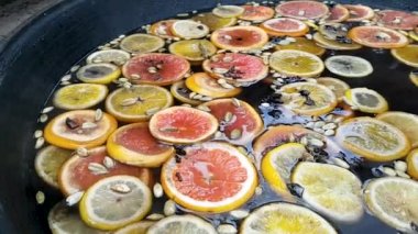 Sıcak şarap içiriyorum. Portakallı limonlu greyfurt ve kakule yakın çekim sıcak su yüzeyinde ve büyük metal bir tencerede kaynatılır. Noel, tatil, gelişim, içki konsepti.