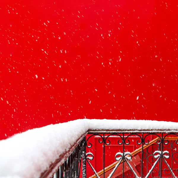Вид на снежный балкон и террасу из кованого металла на фоне красной стены здания во время снегопада. архитектура, зима, открытка, внимание. — стоковое фото