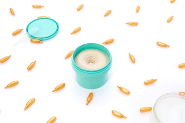 Top view on a bright turquoise jar of cream and golden capsules with collagen on a white background. The concept of beauty, facial skin care, cosmetology, medicine