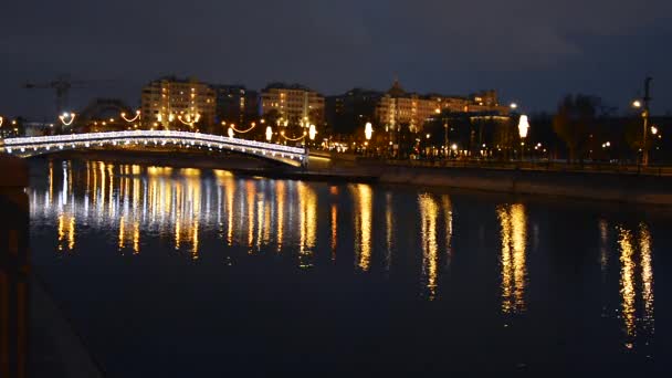 도시의 강 위에 있는 다리의 모습은 조명 과 밤에 물에 반사되는 가로등으로 장식되어 있다. 컨셉 시티, 크리스마스, 건축, 풍경. — 비디오
