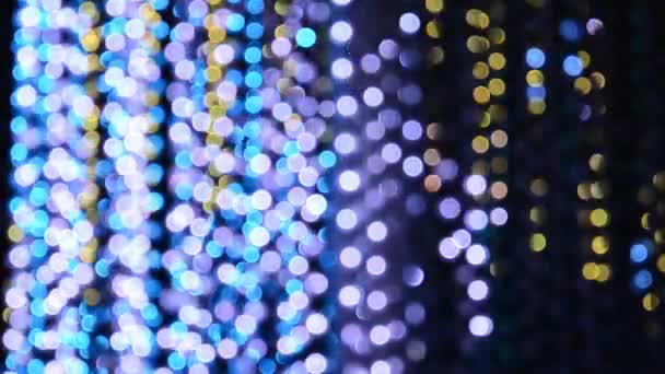 Iluminación de luz de una guirnalda de luces intermitentes en forma de bokeh de blanco, azul, púrpura y oro. El concepto de unas vacaciones, Navidad, iluminación, fiesta . — Vídeo de stock