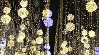 Nikolskaya Caddesi 'ndeki Moskova' da Noel sokağı aydınlığı. Şehir, iplere asılmış parlak toplarla ve titreyen bir arka planda rüzgarda sallanarak tatil için dekore edilmiştir.