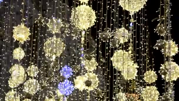 Karácsonyi utcai megvilágítás Moszkvában a Nikolszkaja utcában. város díszített az ünnep fénylő labdák felfüggesztett kötelek és lengő a szél hátterében villogó bokeh — Stock videók