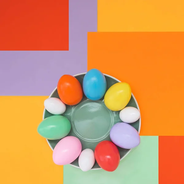 Bright background with a non-symmetrical geometric pattern in a fashionable color scheme with a composition of their Easter eggs that lie on a plate. Concept background, holiday, easter, children\'s creativity