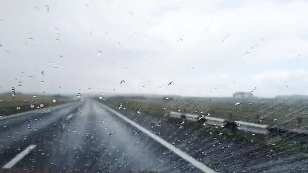 Знімок дощових крапель, які течуть по лобовому склі автомобіля, який їде на автобані в дощову погоду . — стокове відео