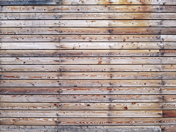 A solid wall of aged brown wooden planks with hammered nails located horizontally. Concept for texture, background, interior