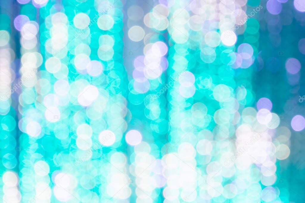 Bright background from blurry bokeh of Christmas lights in turquoise and white. Holiday concept, background, christmas