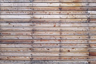 Yatay olarak yerleştirilmiş çekiç çivili eski kahverengi ahşap tahtalardan oluşan katı bir duvar. Doku, arkaplan, iç mekan kavramı