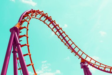 Mavi gökyüzüne karşı turuncu ve pembe roller coaster tasarımı