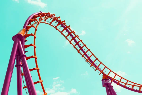 Mavi gökyüzüne karşı turuncu ve pembe roller coaster tasarımı