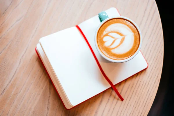 Kopp cappuccino med notebook — Stockfoto