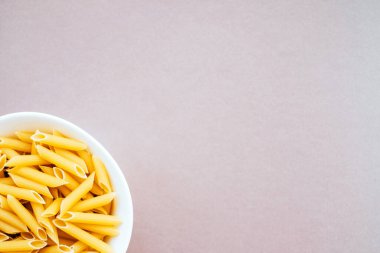Beyaz arka plan üzerinde izole kase çiğ penne rigate makarna. Flatlay stil, üstten görünüm. Geleneksel İtalyan mutfağı.