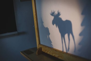 Öğretmen anaokulunda ya da anaokulunda geyik taklidi yapıyor. Çocuklar için gölge pandomim gölge grafiği