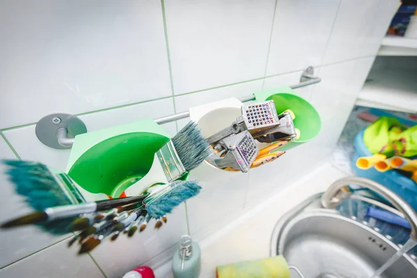 Resim atölyesinde çizim aletleri. Üstten açıyla, paletteki boya fırçalarının, yağlı boya fırçalarının fırça darbelerinin, büyük püsküllerin fotoğrafını göster.