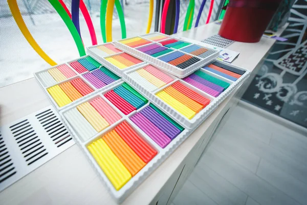 Yeni açılan çok renkli kil plastiksi yalanlar. Okuldaki, anaokulundaki ya da eğitim merkezindeki çizim odasındaki kil plastikinin geniş açılı fotoğrafı. Atmosfer çiz.