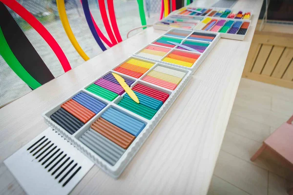 Yeni açılan çok renkli kil plastiksi yalanlar. Okuldaki, anaokulundaki ya da eğitim merkezindeki çizim odasındaki kil plastikinin geniş açılı fotoğrafı. Atmosfer çiz.