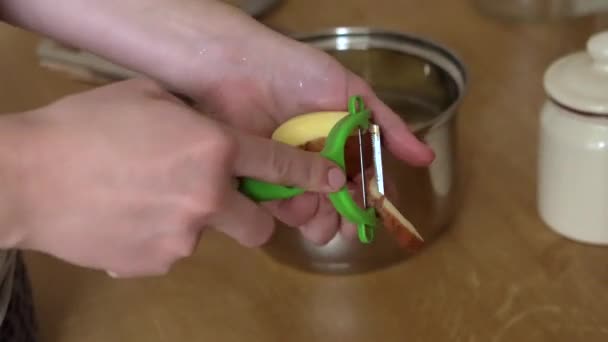 Vrouw handen peeling aardappelen in de keuken — Stockvideo