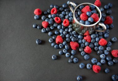 Ahududu ve yaban mersini arka plan. Ahududu ve yaban mersini kopya alanı siyah zemin üzerine. Yaz ve sağlıklı gıda kavramı, üstten görünüm veya düz lay.