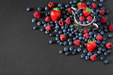 Ahududu, çilek ve yaban mersini arka plan. Berry kopya alanı siyah zemin üzerine. Yaz ve sağlıklı gıda kavramı, üstten görünüm veya düz lay.