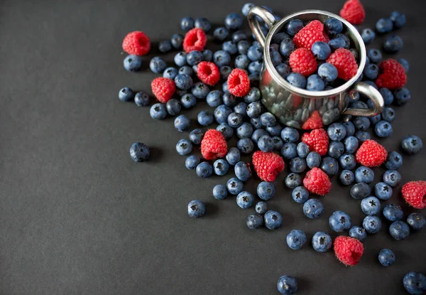Ahududu ve yaban mersini arka plan. Ahududu ve yaban mersini kopya alanı siyah zemin üzerine. Yaz ve sağlıklı gıda kavramı, üstten görünüm veya düz lay.
