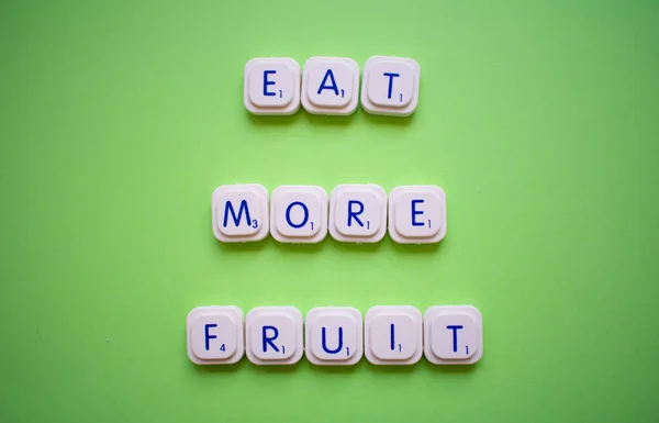 Motivációs szlogen: Egyél több gyümölcsöt, zöld háttérrel, játékbetűkkel — Stock Fotó